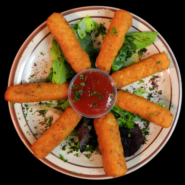 Golden-brown fried cheese sticks arranged in a circle with a cup of red dipping sauce and greens.