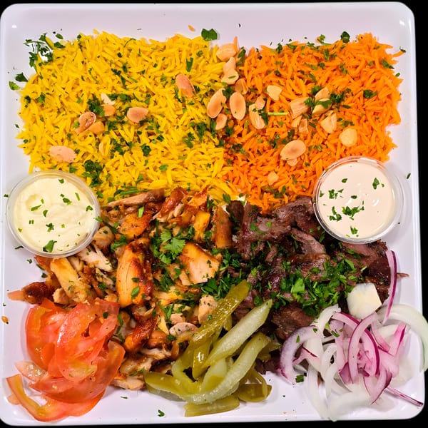 Mediterranean platter with yellow and orange rice, chicken and beef shawarma, tomatoes, pickles, and sauces.