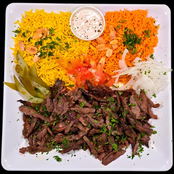 Desert Moon Mediterranean Grill's beef shawarma plate with yellow and orange rice, pickles, tomatoes, onions, and sauce.
