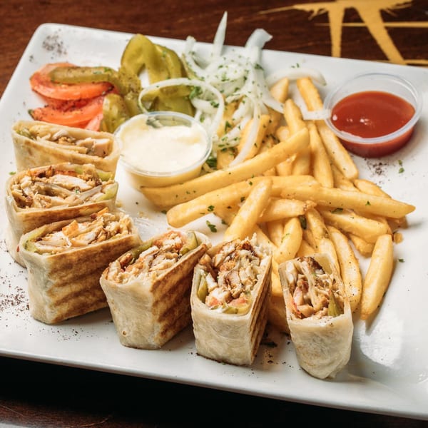 Mediterranean chicken shawarma wraps, fries, and dipping sauces on a white plate.