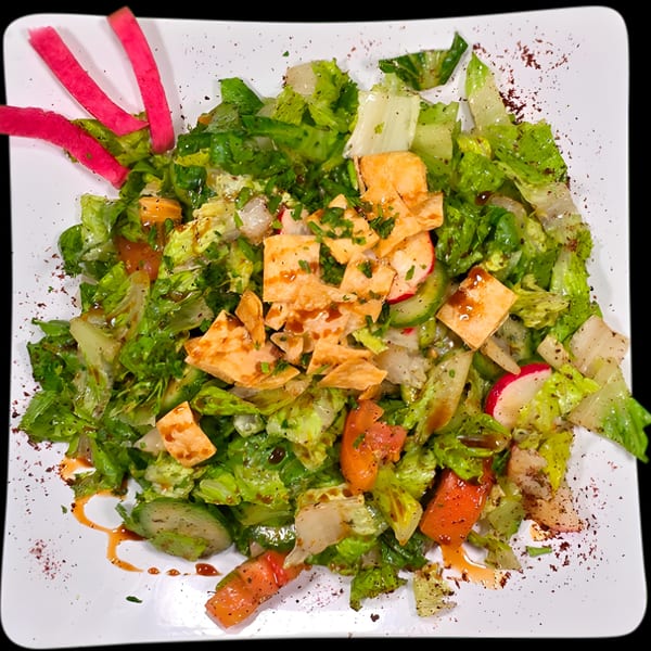 A vibrant Mediterranean fattoush salad with lettuce, tomatoes, cucumbers, radishes, and crispy pita.